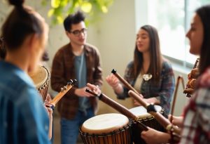 Un groupe de collègues tenant des instruments de musique, participant à un cercle de percussions pour un team building sous une lumière naturelle douce.