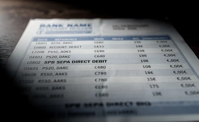 Gros plan photoréaliste d’un relevé bancaire européen montrant une ligne de prélèvement SPB SEPA dans une lumière contrastée.