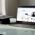 Un ordinateur portable moderne affichant une interface de MBA en ligne repose sur un bureau élégant, accompagné d’un mortier de diplômé sous une lumière matinale douce.