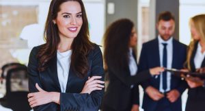 Femme manager souriante bras croises devant son equipe dans un bureau