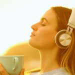 Femme avec casque audio les yeux fermes ecoutant de la musique en streaming