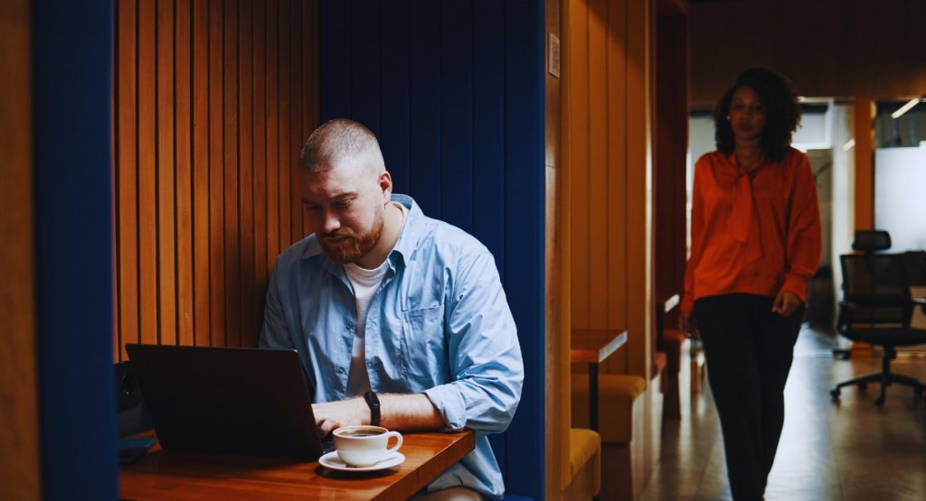 Homme travaillant sur son ordinateur portable dans une cabine de bureau insonorisee en bois